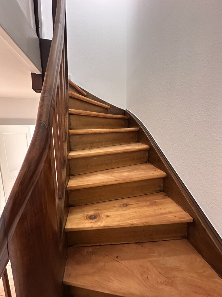 Fachgerecht restaurierte, historische Holztreppe mit geschwungenem Handlauf in einem sanierten Altbau in Basel.